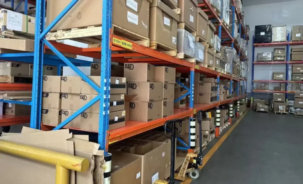 CAT genuine parts warehouse storage with organized shelves of boxes, drums, and crates for heavy equipment inventory
